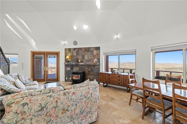 tiled living room with french doors, a mountain view, vaulted ceiling, and a wood stove