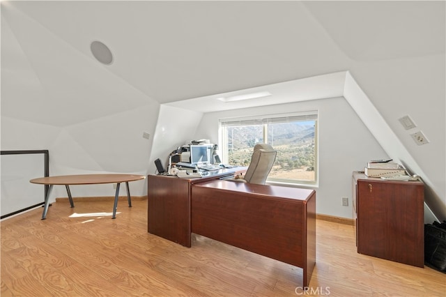 home office with lofted ceiling and light hardwood / wood-style floors