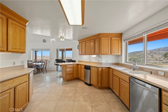 kitchen featuring light tile patterned flooring, a mountain view, vaulted ceiling, kitchen peninsula, and stainless steel dishwasher