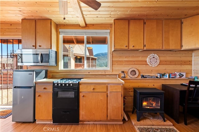 kitchen featuring beamed ceiling, light hardwood / wood-style flooring, wood ceiling, a wood stove, and appliances with stainless steel finishes