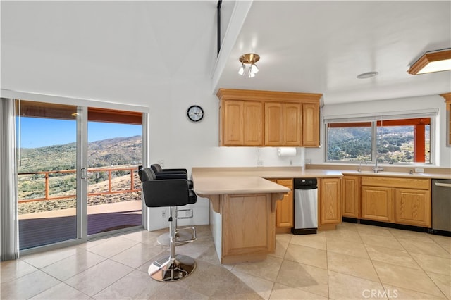 kitchen featuring a mountain view, light tile patterned flooring, kitchen peninsula, and stainless steel dishwasher