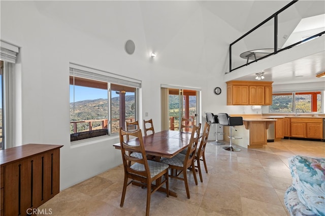 dining room with high vaulted ceiling, a mountain view, and a wealth of natural light