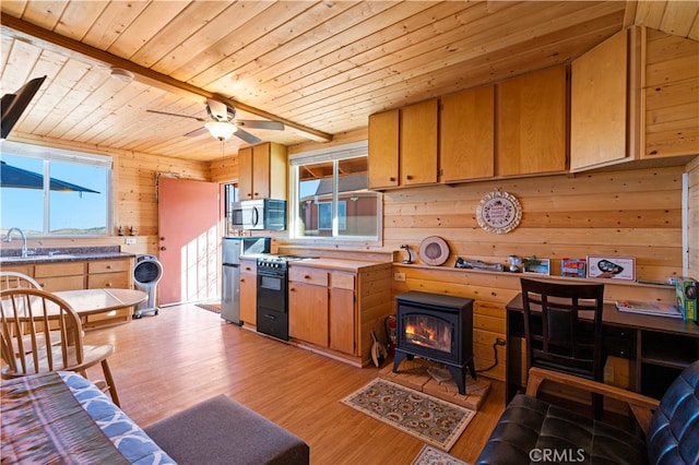 kitchen with black range with electric stovetop, wood walls, a wood stove, light hardwood / wood-style flooring, and wooden ceiling