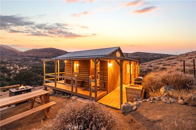 back house at dusk featuring an outdoor fire pit and a deck with mountain view