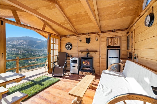 living room featuring vaulted ceiling with beams, a mountain view, wooden walls, light hardwood / wood-style flooring, and wooden ceiling