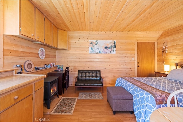 bedroom featuring a wood stove, wood walls, wood ceiling, and light hardwood / wood-style flooring