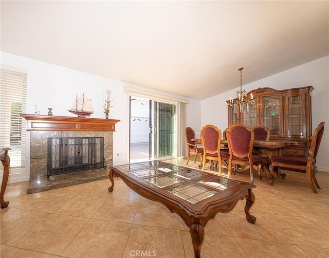 living room featuring light tile patterned flooring, a healthy amount of sunlight, a premium fireplace, and a notable chandelier