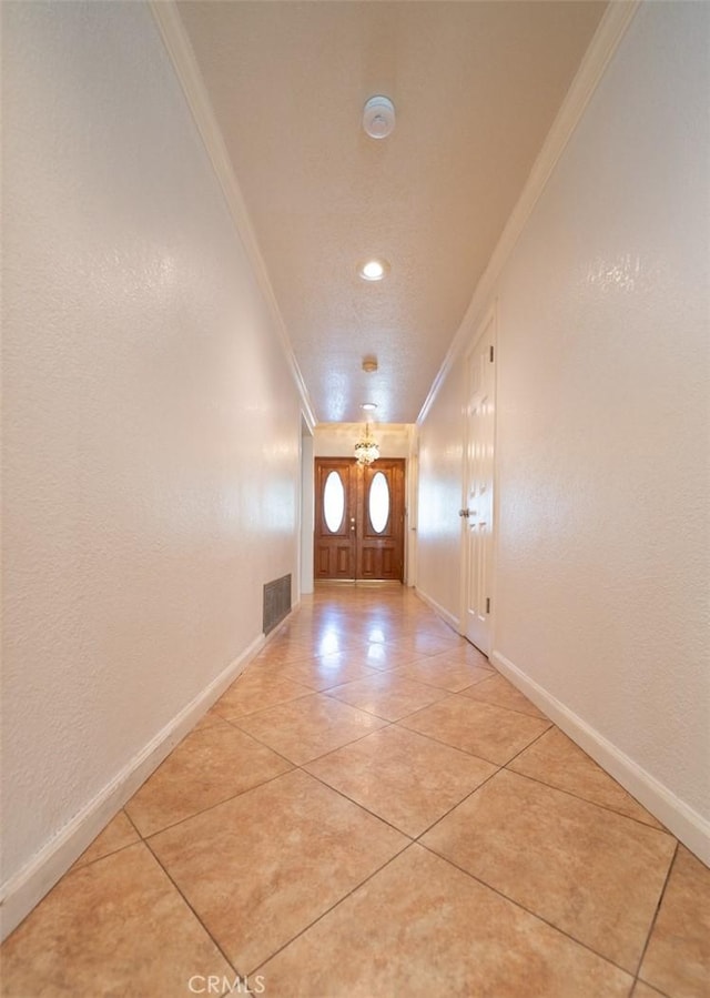 doorway with ornamental molding and light tile patterned flooring