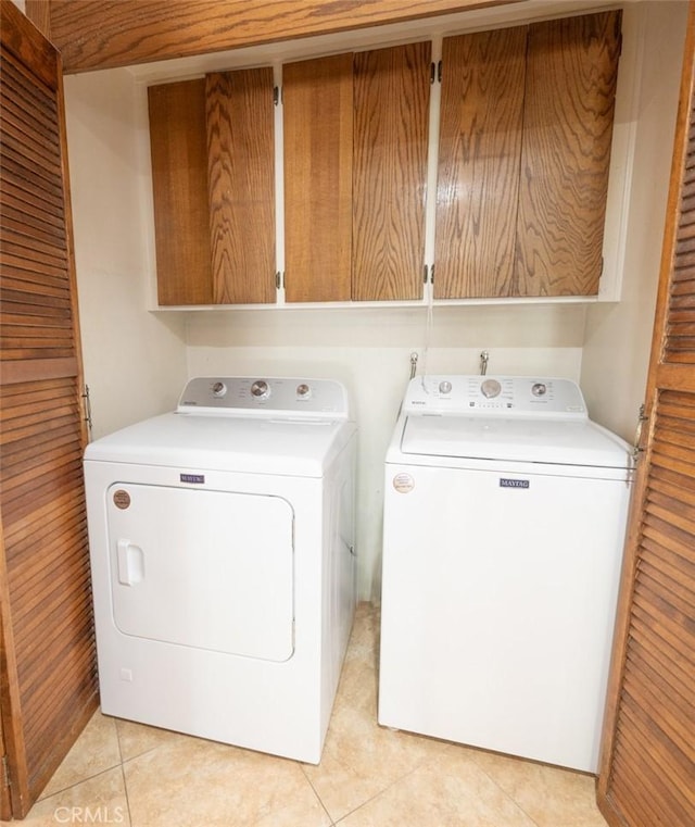 laundry room with cabinets, light tile patterned floors, and washer and clothes dryer