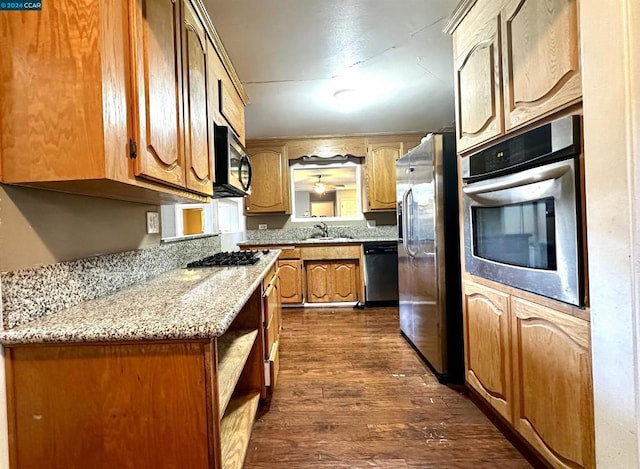 kitchen with light stone countertops, dark wood-type flooring, appliances with stainless steel finishes, and sink