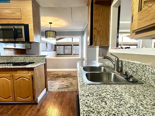 kitchen with sink, hanging light fixtures, gas stovetop, ornamental molding, and dark hardwood / wood-style flooring