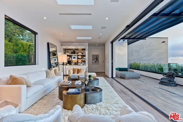 living room with light wood-type flooring and a skylight