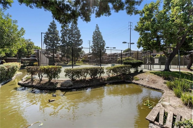 view of home's community featuring tennis court and a water view