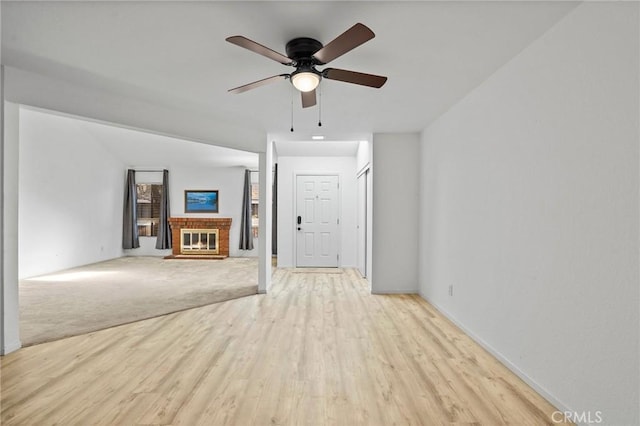 unfurnished living room featuring ceiling fan, a fireplace, and light hardwood / wood-style flooring