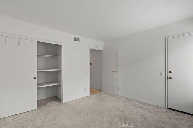 unfurnished bedroom featuring light colored carpet and a closet