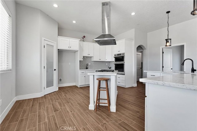 kitchen with island exhaust hood, white cabinetry, a healthy amount of sunlight, and sink