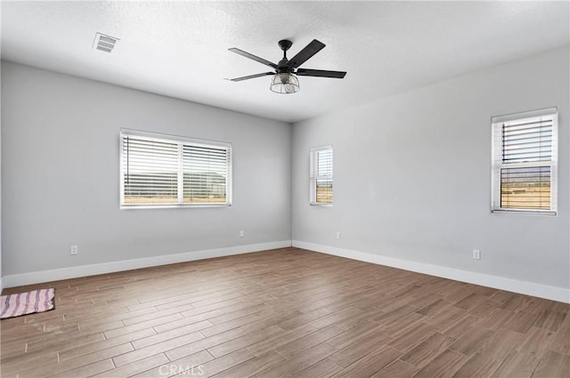 spare room featuring hardwood / wood-style flooring, ceiling fan, a textured ceiling, and a wealth of natural light