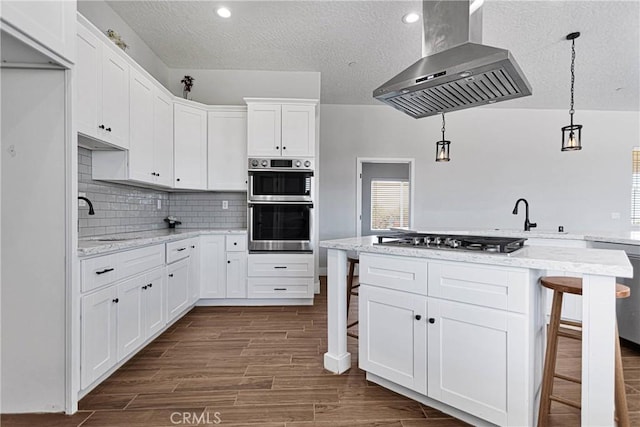 kitchen with a breakfast bar area, extractor fan, a textured ceiling, and appliances with stainless steel finishes