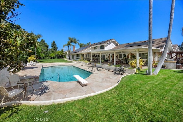 view of pool featuring a diving board, a yard, and a patio