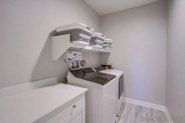 laundry area featuring cabinets, washing machine and dryer, and light hardwood / wood-style floors