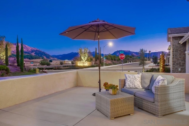 patio terrace at dusk featuring a balcony and a mountain view