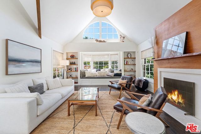 living room with built in shelves, light hardwood / wood-style flooring, and high vaulted ceiling