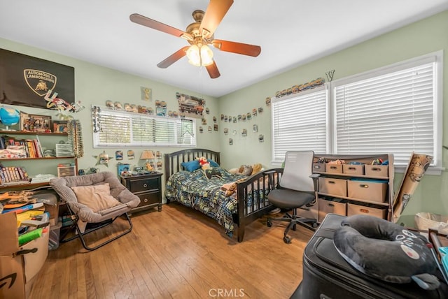 bedroom featuring multiple windows, hardwood / wood-style floors, and ceiling fan