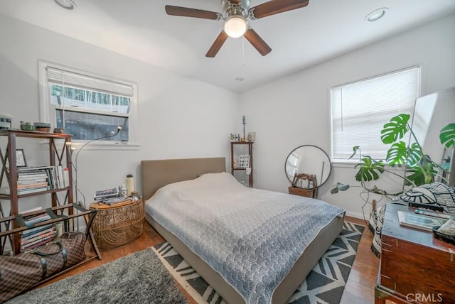 bedroom with multiple windows, dark wood-type flooring, and ceiling fan