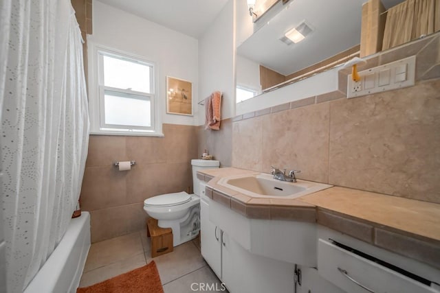 full bathroom featuring tile walls, vanity, toilet, tile patterned floors, and shower / bath combo with shower curtain