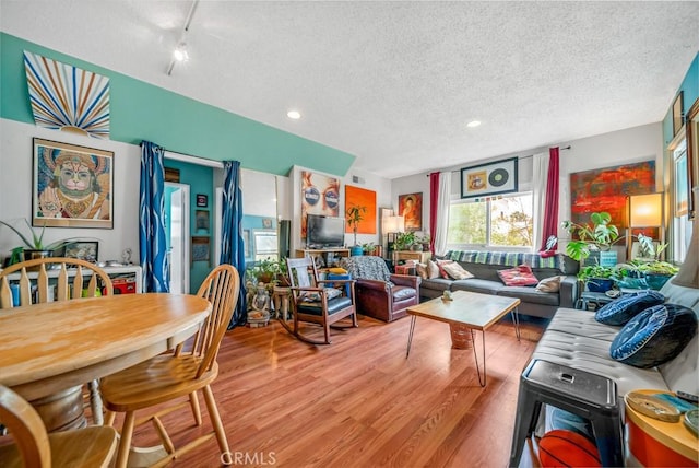 living room with track lighting, light hardwood / wood-style floors, and a textured ceiling