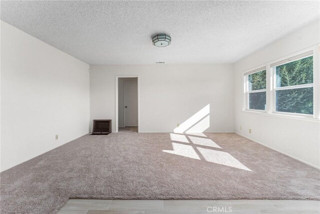 empty room featuring light carpet and a textured ceiling