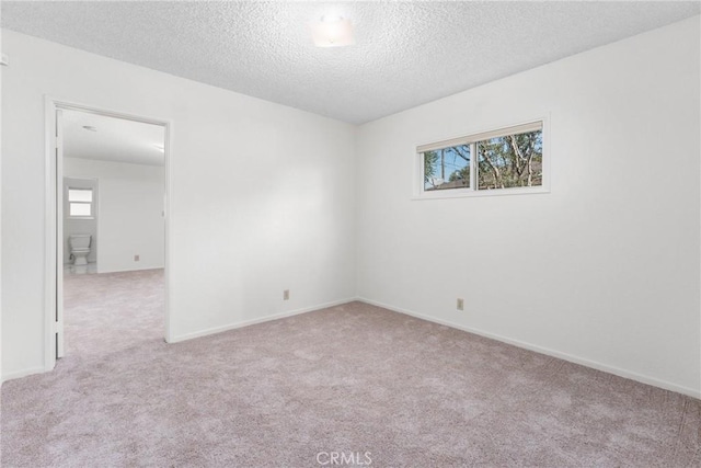 empty room with light carpet and a textured ceiling