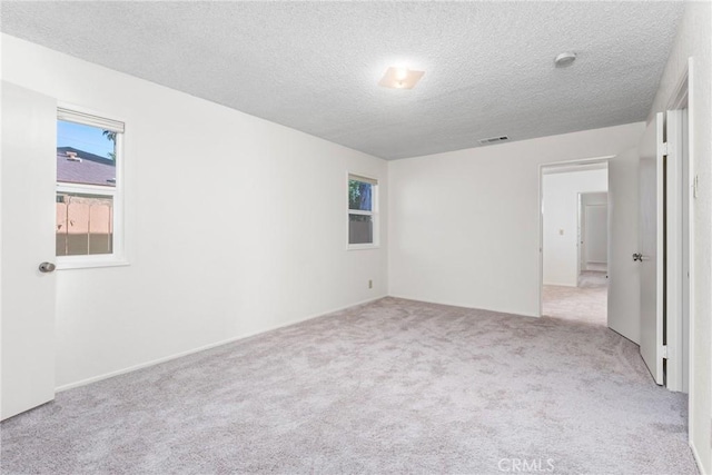 empty room featuring a textured ceiling and light colored carpet