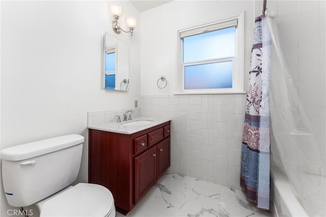 full bathroom with marble finish floor, a wainscoted wall, tile walls, toilet, and vanity