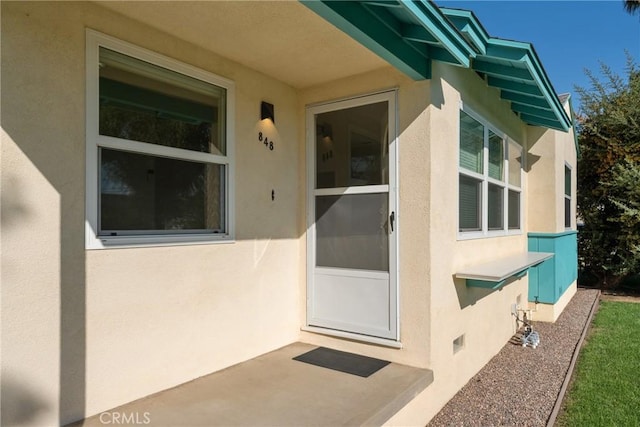 doorway to property featuring crawl space and stucco siding