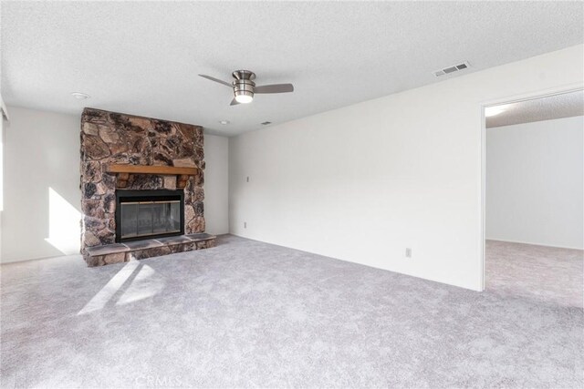 unfurnished living room featuring a textured ceiling, ceiling fan, a fireplace, and carpet floors