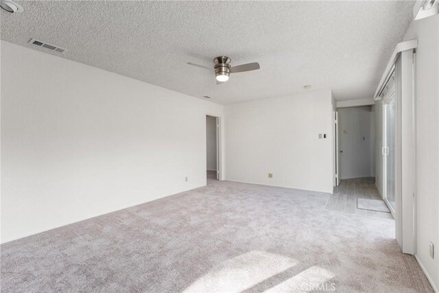 carpeted empty room with ceiling fan and a textured ceiling