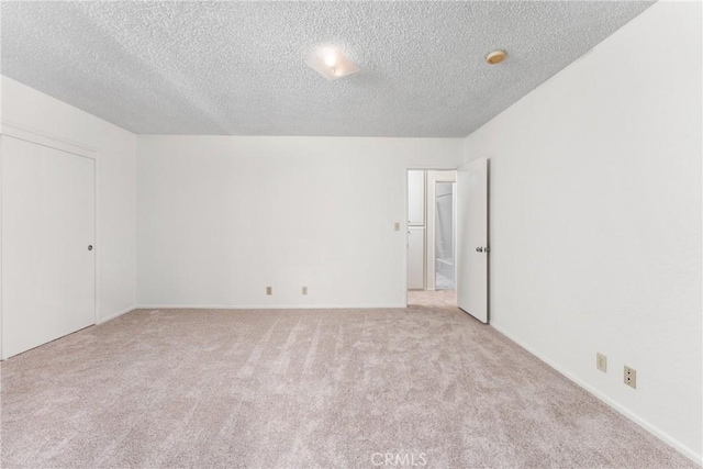 spare room with light colored carpet and a textured ceiling