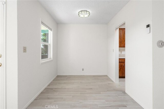 spare room featuring light hardwood / wood-style floors and a textured ceiling