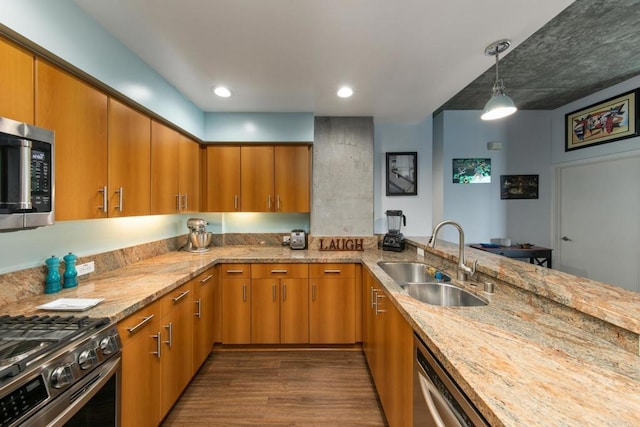 kitchen featuring a peninsula, appliances with stainless steel finishes, brown cabinets, and a sink