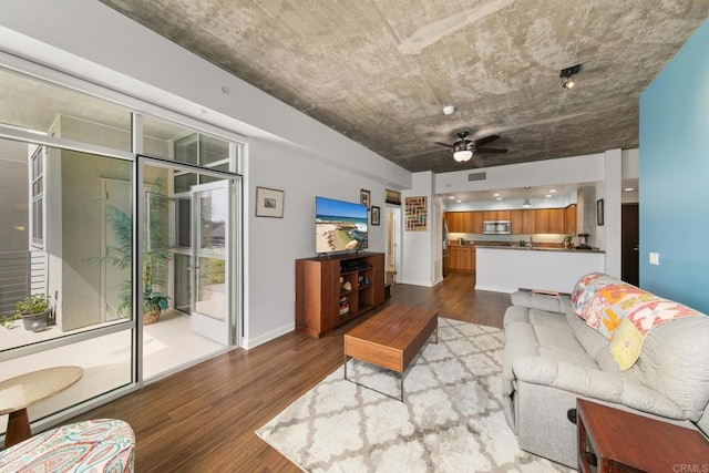 living room with wood finished floors, a ceiling fan, and baseboards