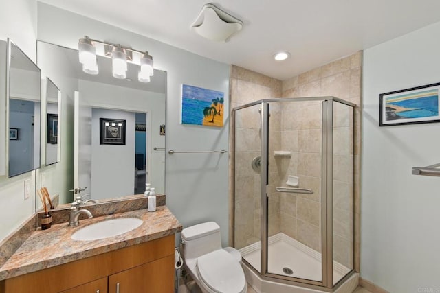 full bath featuring toilet, a shower stall, and vanity