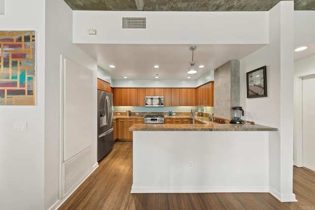 kitchen featuring pendant lighting, brown cabinets, visible vents, appliances with stainless steel finishes, and a peninsula