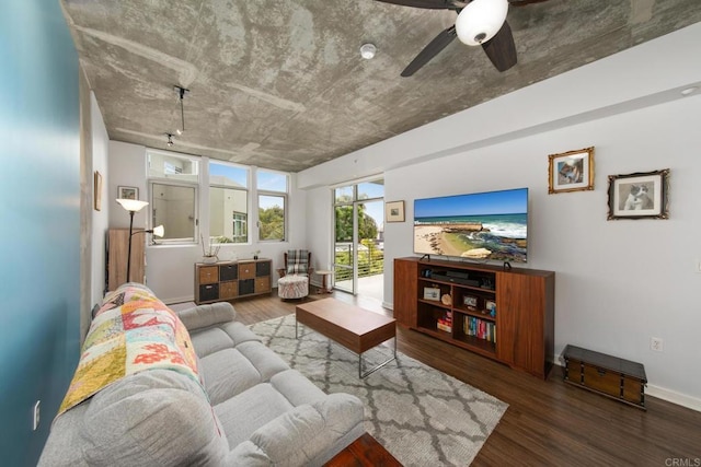 living area with dark wood-style floors, ceiling fan, and baseboards