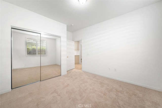 unfurnished bedroom featuring light colored carpet and a closet