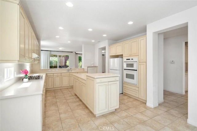 kitchen with sink, a center island, white appliances, and cream cabinetry