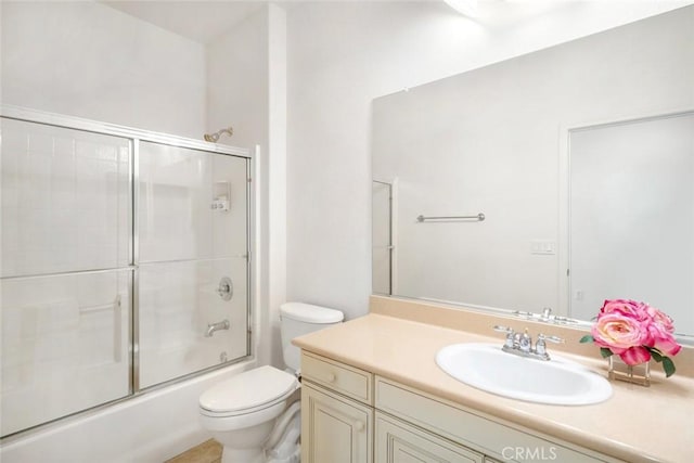 full bathroom featuring toilet, combined bath / shower with glass door, and vanity