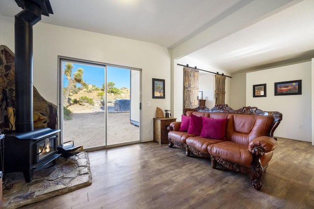 living room featuring lofted ceiling with beams, a wood stove, hardwood / wood-style floors, and a barn door