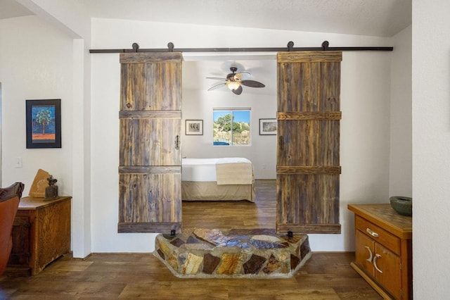 bedroom with ceiling fan, vaulted ceiling, dark hardwood / wood-style floors, and a barn door