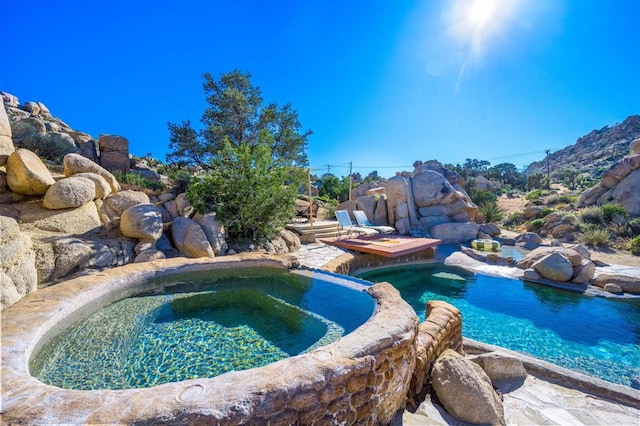 view of pool featuring an in ground hot tub and a small pond